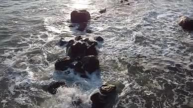 夕阳下浪花拍打着岩石视频的预览图
